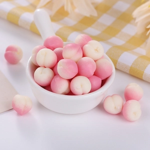 Close-up of realistic mini peach squishy toys in a white bowl for stress relief