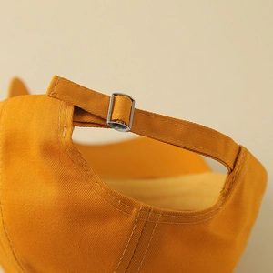 Close-up detail of the adjustable silver metal buckle on a yellow cotton baseball cap strap