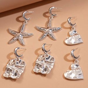 Silver C-shape earrings set featuring starfish, heart, and geometric charms on a warm background