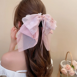 Dettaglio molletta per capelli con fiocco in organza rosa, fiori e nastri di perline