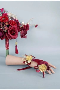 Detail of red and gold Chinese wedding wrist corsage with silk ribbons and metal flowers