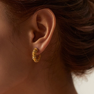 Macro detail of 18K gold-plated C-shape twisted earrings with micro-pave zircons