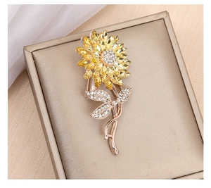 Detail view of sunflower brooch with yellow crystals on a gold jewelry box