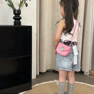 Pink minimalist crossbody bag for kids with silver buckle shown in a lifestyle setting
