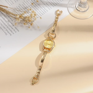 Close-up of a women's vintage gold bangle watch with a polished metal strap and Roman dial