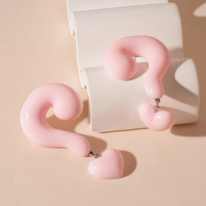 Detail shot of pink resin question mark earrings with heart charms in Y2K style