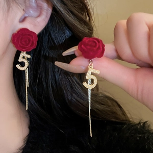 Dettaglio orecchini rosa rossa con pendente perla numero 5 e nappe metalliche