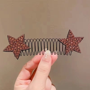 Detail of brown hair comb with rhinestone star ornaments held against a plain wall
