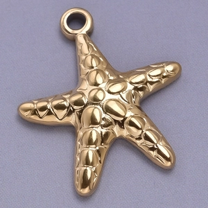 Macro shot of gold stainless steel starfish pendant with textured finish on purple fabric