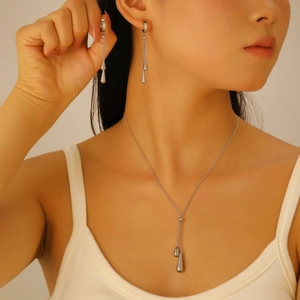 Macro detail of polished silver teardrop pendant and elegant long snake chain necklace