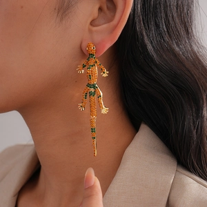 Close-up of luxury gecko drop earring with sparkling green and orange crystals