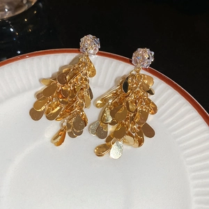 Close-up of golden cluster leaf earrings with zircon studs on a white ceramic plate