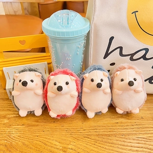 Cute hedgehog plush keychains in four colors arranged on a wooden table with soft decor