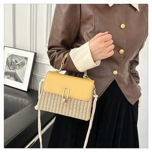 Detailed view of woven straw crossbody bag with yellow leather flap and rope strap