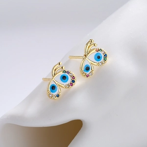 Detail of 18K gold butterfly stud earrings featuring blue evil eye and zircon crystals