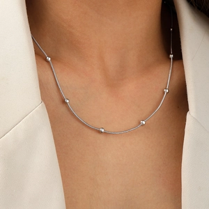 Close-up of a silver stainless steel snake chain necklace with beads on a model