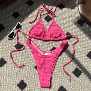 Hot pink smocked bikini set with halter top and high cut bottoms on a patterned rug