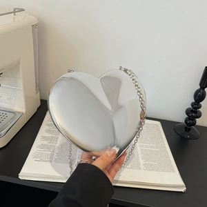 Silver heart-shaped acrylic clutch bag with a reflective mirror finish and chain strap