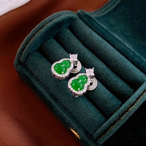 Macro shot of silver gourd earrings with green jade and diamonds in a green velvet box