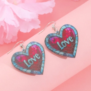 Detailed close-up of acrylic heart-shaped earrings with 'Love' text and checkered patterns