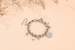 Detail of double-layer titanium steel bracelet featuring Hamsa hand pendant and faux pearls