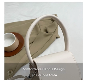 Detail of a creamy white handbag featuring a large circular handle and metal hooks