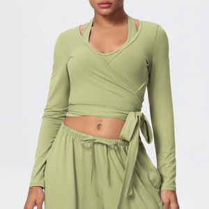 Detail of avocado green V-neck yoga set featuring cross-tie cropped top and wide-leg pants