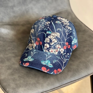 Close-up of floral print patterns on distressed denim baseball cap with curved brim