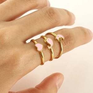 Three-piece gold alloy rings set featuring pink enamel heart, dolphin and moon designs