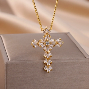 Close-up of golden cross pendant with baguette-cut and round zircons on satin