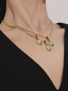Gros plan du collier doré multicouche avec pierres vertes en forme de goutte