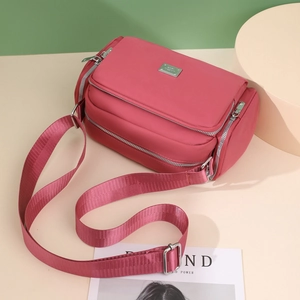 Bolso bandolera de nailon magenta con correa ancha y varios bolsillos con cremallera