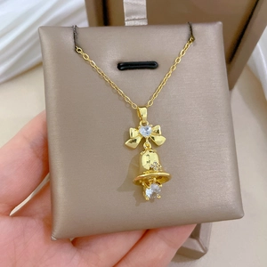 Close-up of golden bow-knot bell pendant necklace with sparkling zircons in a jewelry box