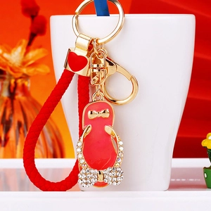 Macro view of a red rhinestone flip-flop keychain with braided strap and heart charm