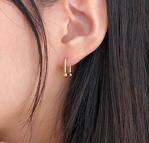 Close-up of a 925 sterling silver geometric U-shaped earring with golden finish on ear