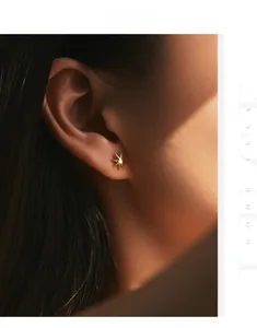 Detail of s925 silver golden sunburst stud earring worn by a model with artistic light