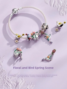 Close-up of S925 silver charm bracelet with floral enamel beads and bird charms
