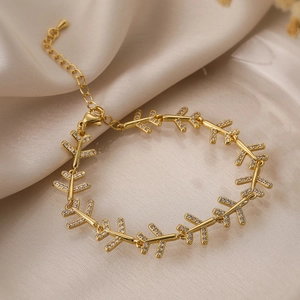 Gold-plated airplane heart bracelet with sparkling zircons on white silk background