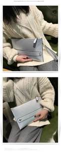 Zilveren envelop clutch tas met kiezelkorrel textuur en polsbandje vastgehouden