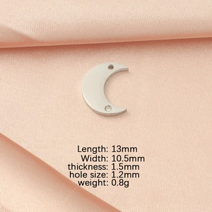 Macro view of a moon-shaped silver pendant with dimensions 13x10.5mm on pink fabric
