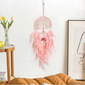 Roze levensboom dromenvanger met veren en kralen aan een witte muur hangend