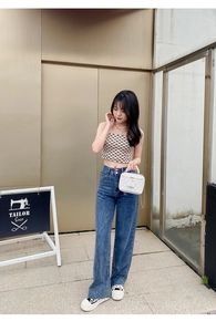 Street style shot of a white quilted chain bag with a pearl handle and denim jeans
