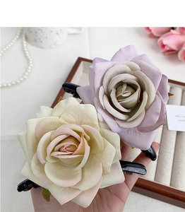 Detailed view of artificial rose hair claws in beige and lavender on elegant jewelry tray