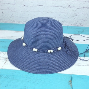 Detail of blue straw sun hat with woven spiral texture and elegant white bead trim decoration