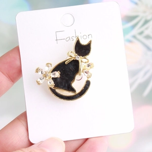 Detail of elegant black cat brooch with gold trim and sparkling crystal flower accent