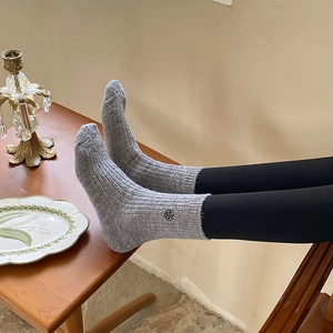 Close-up of gray ribbed knit warm socks with a delicate black flower embroidery detail