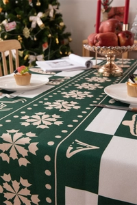 Detailed view of green Christmas tablecloth with snowflake patterns and festive setting