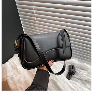 Detail of black matte leather shoulder bag featuring gold hardware and removable strap