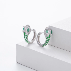 Macro shot of silver snake earrings with green enamel scales and sparkling crystals