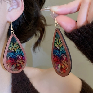 Detail view of retro teardrop wood earrings with colorful mosaic patterns on a model